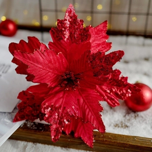 Red artificial Christmas poinsettia flower with sequins on white snow background