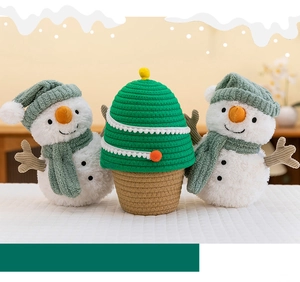 Detail of plush Christmas snowmen and a woven tree basket on a cozy white tablecloth