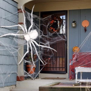 Detail of a large white plush Halloween spider with red eyes on a stretchable spider web