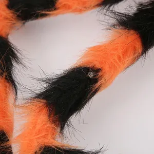 Macro detail of Halloween giant spider leg with orange-black plush fur and LED light