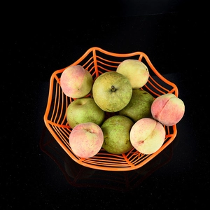 Corbeille à fruits orange en toile d'araignée avec pêches et poires sur fond noir