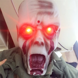 Detailed close-up of a scary Halloween zombie prop featuring glowing red LED eyes and torn fabric