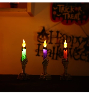 Close-up of three LED Halloween candles held by skeletal hands with glowing effect