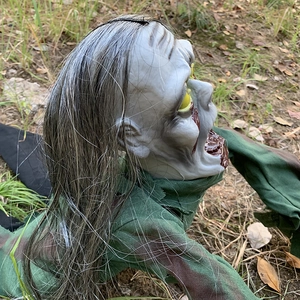 Creepy crawling zombie Halloween prop in camouflage gear on grass for outdoor decor