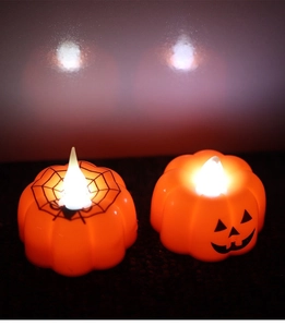 Detail of two orange Halloween pumpkin LED candles with spider web and smiley face designs
