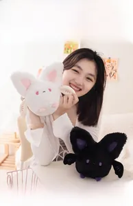 Detailed view of cute round plush bat toys held by a model in black and white colors