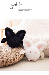 Cute round plush bats in black and white colors on a soft woven mat background