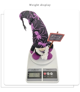 Detail showing a Halloween gnome plush with spider web hat on weight scale at 107.5g