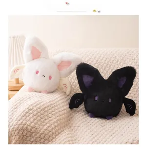 Close-up of cute black and white plush bat toys with big ears and wings on a sofa