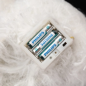 Detail of the battery compartment and power switch hidden within white Halloween plush decor