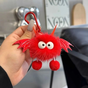 Detail of red plush monster bag charm with big white eyes and red metal carabiner