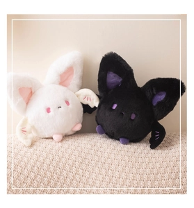 Close-up of cute black and white plush bats with soft fur and colorful inner ears
