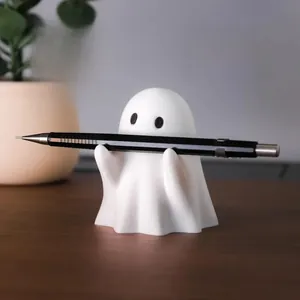 Detailed view of a white ghost pen holder supporting a pencil on a wooden desk surface