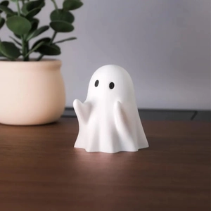 Close-up of cute white ghost figurine on a warm wooden desk with cozy lighting