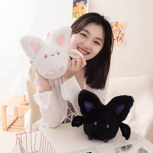 Cute round bat plush toy in black and white colors shown in a cozy home setting