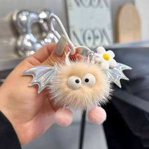 Detail of plush monster keychain with laser bat wings and a small flower decoration