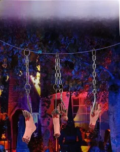 Halloween bloody severed hand and foot props hanging on rusty metal chains for haunted house
