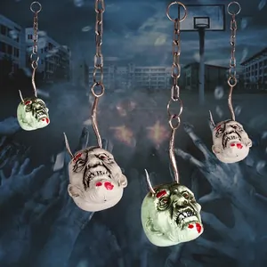 Scary zombie head props hanging on metal chains for Halloween haunted house decoration
