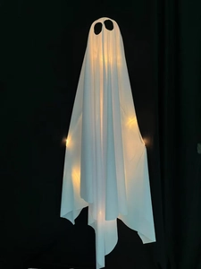 Macro view of a glowing Halloween ghost with warm LED lights and white mesh fabric