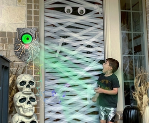 Detail of glowing green eyeball on a spooky spider doorbell for Halloween decoration