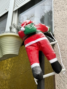Vue de l'escalade du Père Noël sur une échelle de corde sur une fenêtre givrée