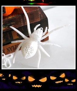 Close-up of white LED Halloween spider pendant with hollow web design on a book