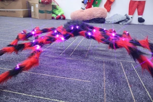 Detail showing glowing purple LED lights on a giant red and black plush Halloween spider