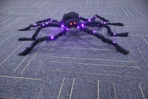 Detail of Halloween spider with glowing red eyes and purple LED lights on fuzzy black legs