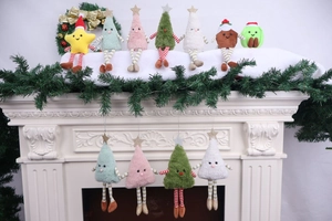 Assorted plush Christmas hanging ornaments with stars and trees on a fireplace mantel
