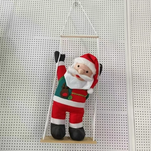 Père Noël sur une balançoire en bois avec vêtements rouges et gilet à motif de renne