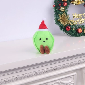 Plush Christmas green veggie doll with red hat on a festive fireplace mantel piece