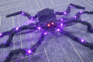 Macro detail of glowing red eyes and purple LED legs on black plush Halloween spider