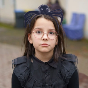 Detail showing a 3D plush black spider headband worn by a child for Halloween party decor