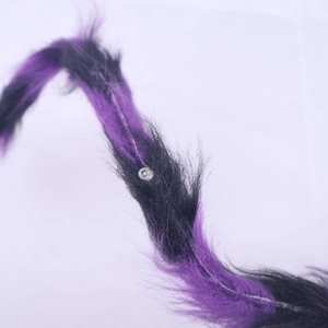 Detailed macro view of purple and black fuzzy plush faux fur with a plastic joint connector