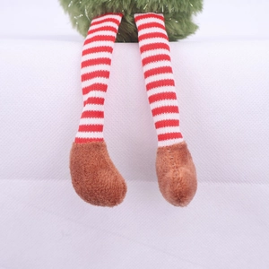Close-up of cute Christmas elf plush doll legs with red striped socks and brown boots