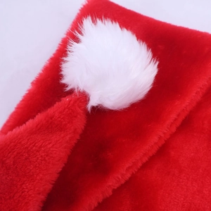 Detailed macro view of the fluffy white pom-pom and red plush fabric of a long Santa hat