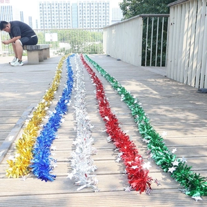 Close-up of colorful 10m tinsel garlands with white stars on a wooden surface