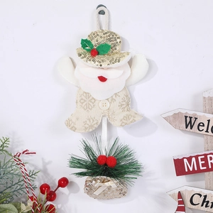 Weihnachtsmann-Plüschanhänger mit Tannennadeln und roten Beeren auf weißer Wand dekoriert