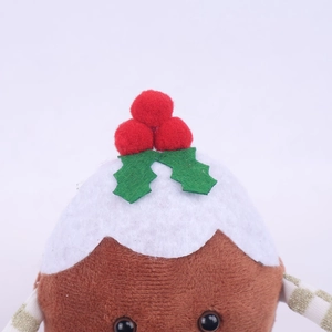 Detailed close-up of a plush Christmas pudding toy featuring green leaves and red berries
