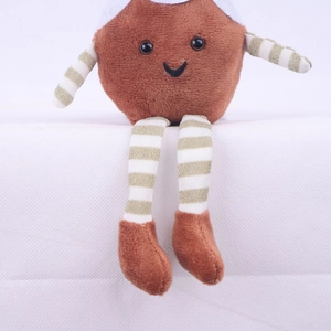 Close-up of plush Christmas doll with embroidered smile and gold striped knit limbs