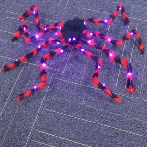 Detail view of a large Halloween spider with purple LED lights and red plush stripe design