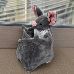 Détail d'une peluche de chauve-souris grise avec oreilles roses et fourrure blanche