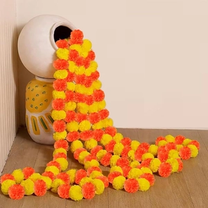 Detail of vibrant orange and yellow marigold garland flowing from a white ceramic vase