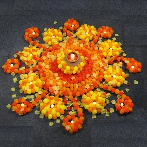 Mandala arrangement of orange marigold flowers with a glowing diya lamp center