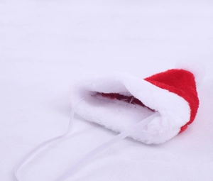 Detailed view of plush red Christmas pet hat with soft white pompom and elastic strap