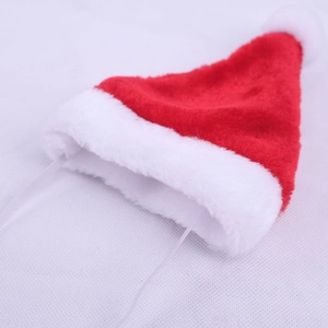 Macro detail of plush red mini Christmas pet hat with fluffy white pompom and elastic strap