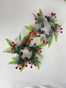 Dettaglio di ghirlande natalizie per candele con aghi innevati e bacche rosse
