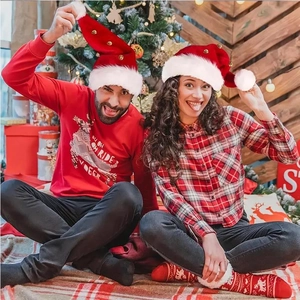 Detail of red Santa hats with gold bells and reindeer sweaters in a Christmas scene