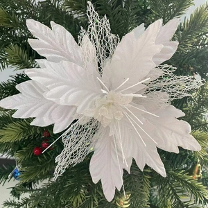 White poinsettia flower ornament with silver glitter on Christmas tree branches