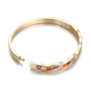 Detail of gold wave bangle with baguette-cut rainbow stones and hinge clasp